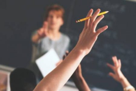 Teacher pointing to raised hands in classroom